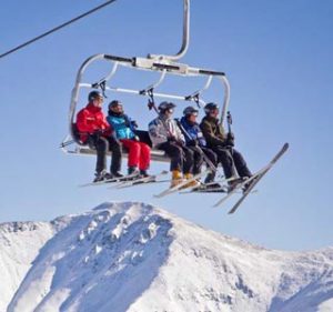 A group of five takes a ride on the chairlift while skiing in Colorado.
