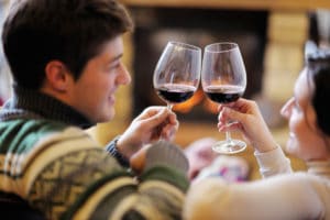A young couple clang glasses of wine to celebrate their romantic getaway in Colorado.
