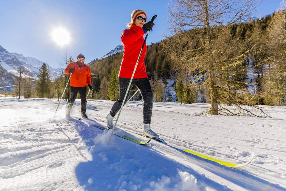 couple gliding down vail cross country skiing trails during a sunny winter day